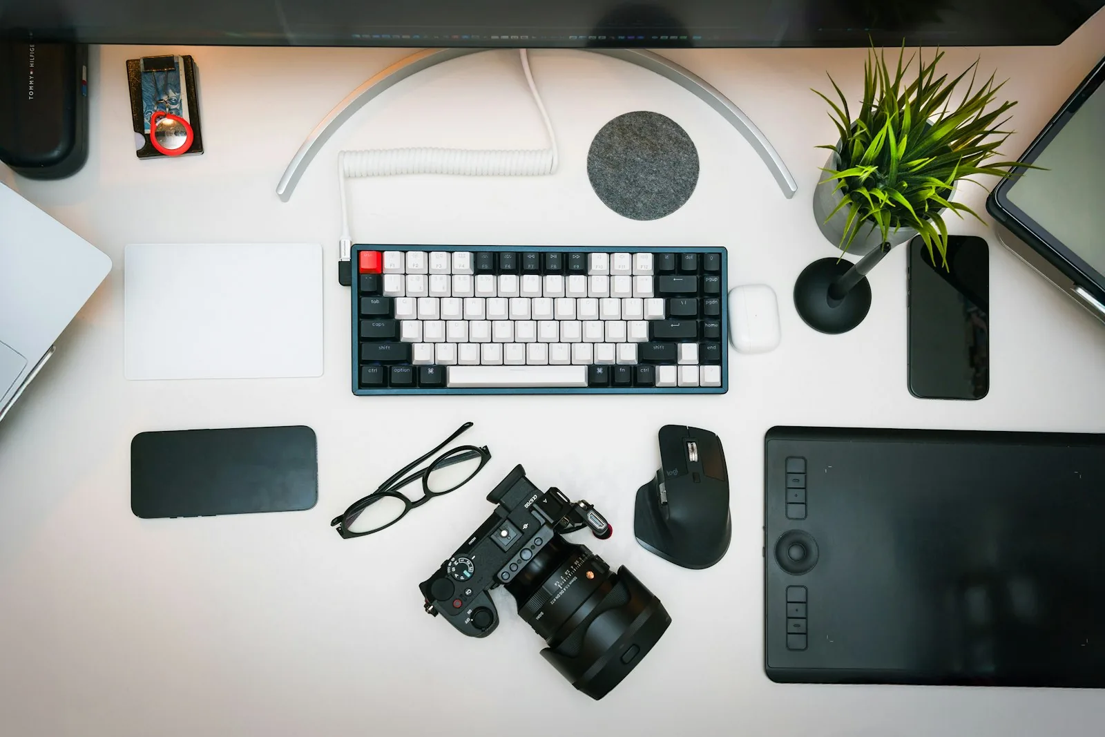 A photographer's desk with a camera, keyboard and mouse, representing the post-event photo delivery workflow
